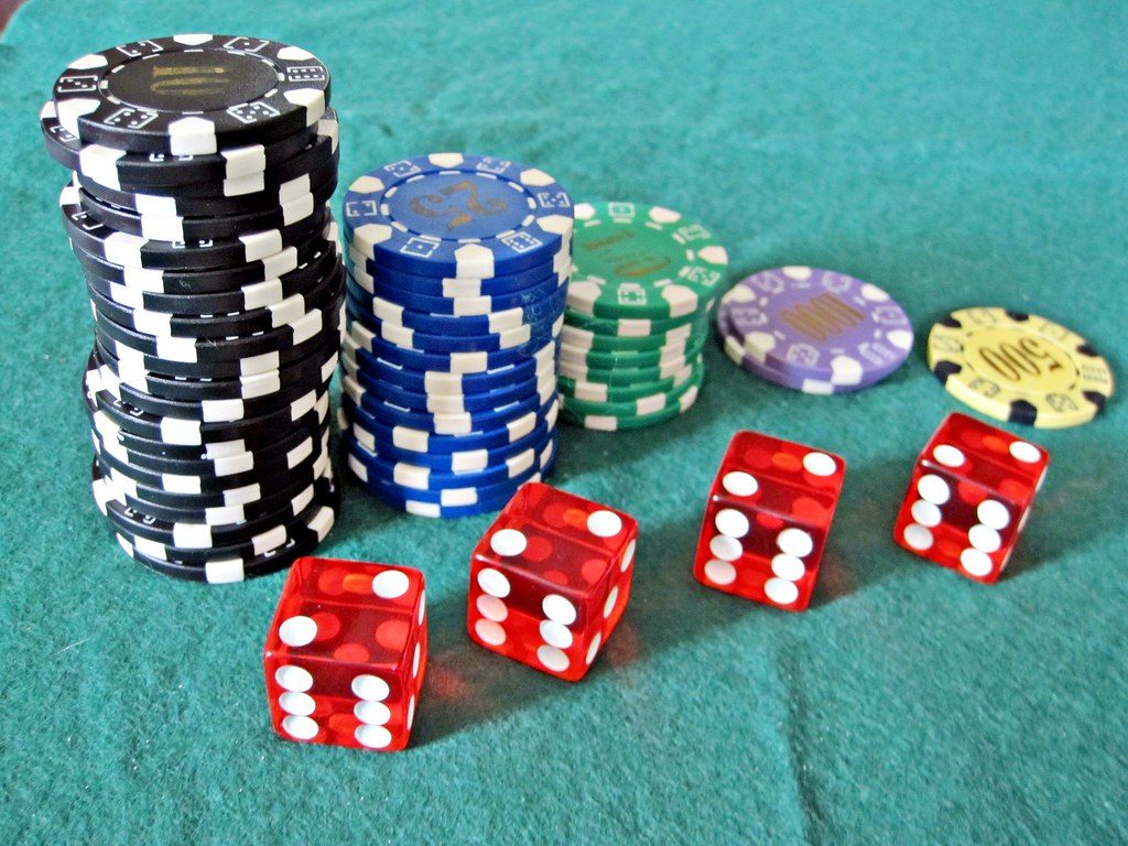 Red casino dice and poker chips on a green felt gaming table